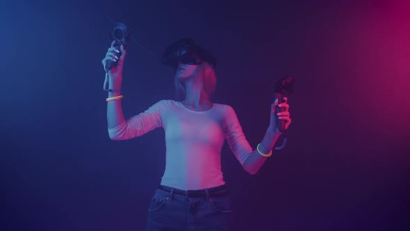 Caucasian Girl in Virtual Reality Glasses Wearing Casual Clothes Holding Controllers Joysticks 