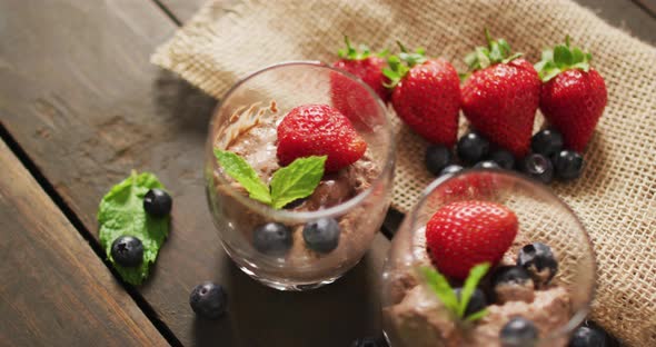 Video of chocolate pudding with strawberries and bluberries on a wooden surface