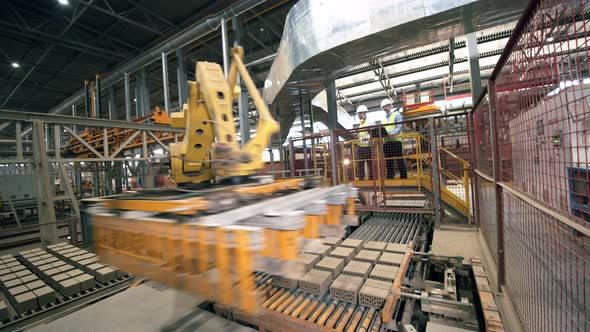 Robotic Industrial Equipment Under Control of Two Engineers at Modern Factory.