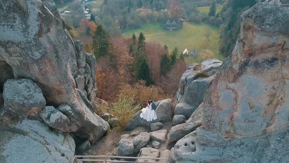 Newlyweds Stand on a High Slope of the Mountain