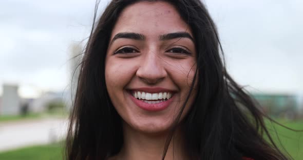 Young indian woman smiling on camera at city park