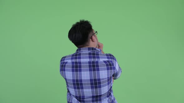 Rear View of Young Overweight Asian Hipster Man Pointing Finger and Directing