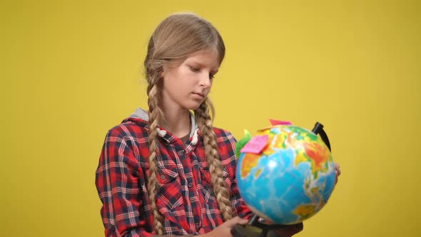 Portrait of Serious Adolescent Caucasian Girl at Yellow Background with Globe and Adhesive Stickers