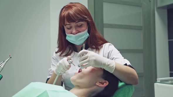 Young Female patient with open mouth examining dental inspection at dentist office. Dental clinic.