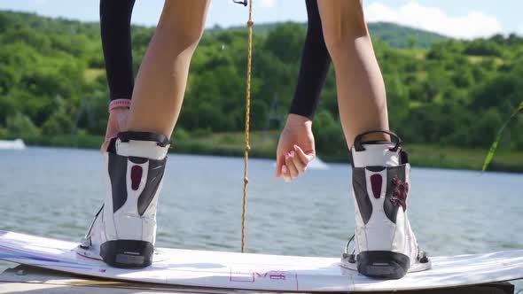 Close Up of Woman Binding Boots of Wakeboarding Board