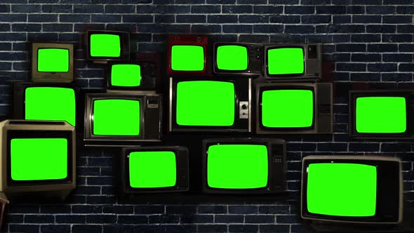 Pile of Retro Vintage TVs Turning On Green Screens over Black Brick Wall.