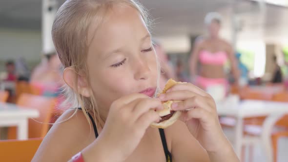 Beautiful Happy Hungry Baby Girl Eating Hamburger. Fast Food Concept. Tasty Unhealthy Burger