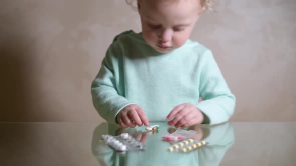 A little girl is playing with different pills that she found on the table