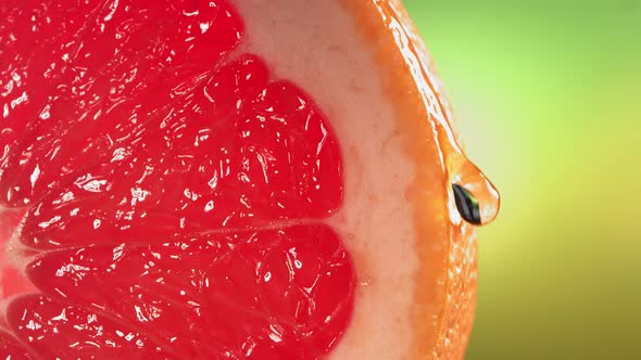 Drop of Water Flows Down the Surface of a Ripe Juicy Grapefruit Slice