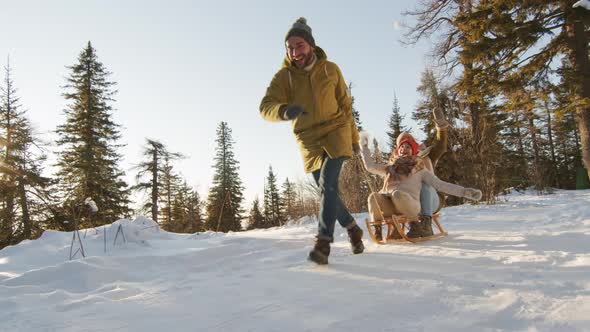 Friends Having Fun Sledding In Forest