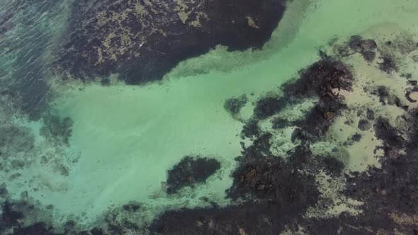 Aerial drone footage of the sea and the coral reef at sunset in Lanzarote island, Spain.