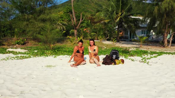 Beautiful women tanning on idyllic lagoon beach journey by transparent sea and white sand background