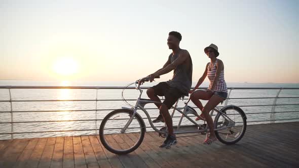 Portrait of a Mixed Race Couple Riding on Tandem Bicycle Outdoors Near the Sea