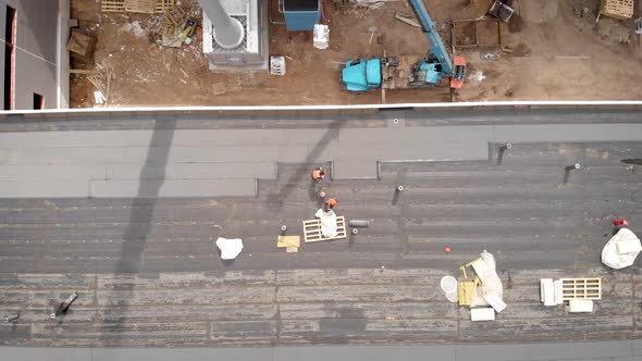 Workers at a Construction Site. The Process of Hydro Insulation of the Roof. With the Help of a alt