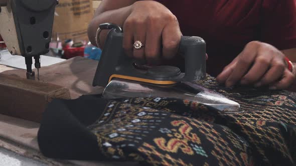 Seamstress Ironing a Finished Garment at the Market