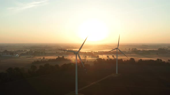 Drone Shot on a Wind Farm Tower in a Field at Sunrise with Fog