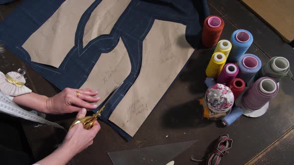 Hands of Dressmaker Cutting Patterns with Scissors