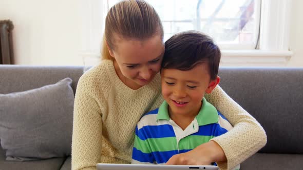 Mother and son using digital tablet in living room