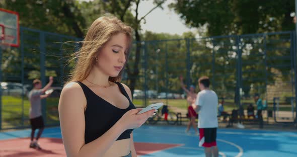A Sporty Girl is Texting on Her Smartphone