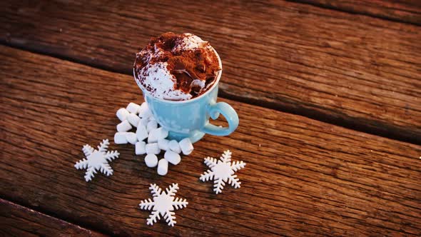 Coffee mug with cocoa powder and snowflakes on a plank