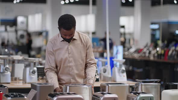 Male Shopper with Face Mask is Choosing Toaster Viewing Exhibition Samples Man is Shopping in