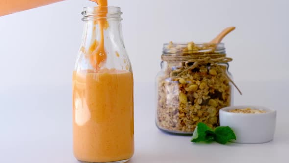 Slow Motion Seasonal Pumpkin Carrot Smoothie Drink Detox Pouring in Glass Bottle with Eco Metal