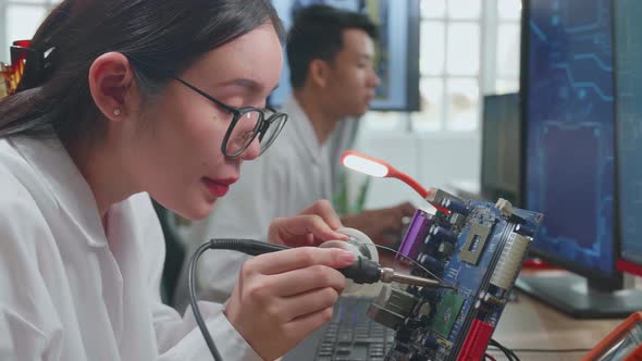 Development Facility: Beautiful Asian Female Engineer Does Computer Motherboard Soldering