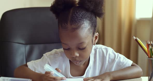 Portrait of Cute African American Girl Draws While Sitting at Table, Uses Markers Colored Pencils