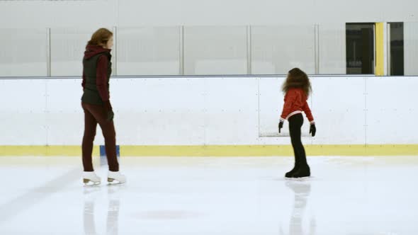 Woman Training with Little Girl on Ice Rink