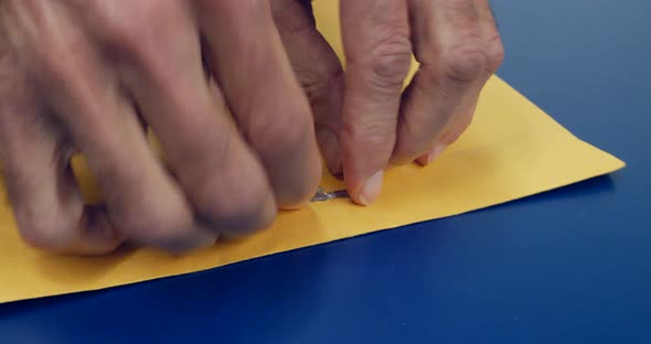 Close up on hands opening a yellow envelope with important document inside after being mailed and de