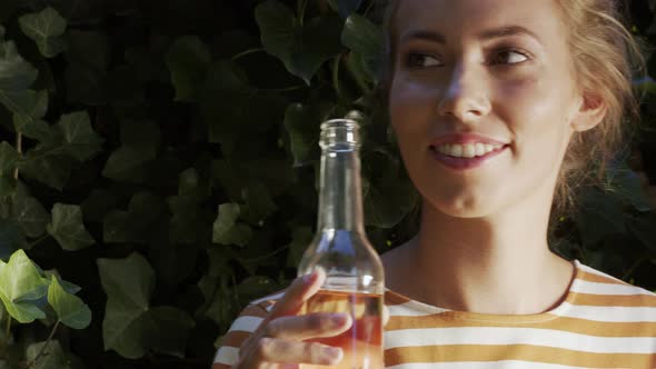 Woman drinking lemonade in front of ivy wall