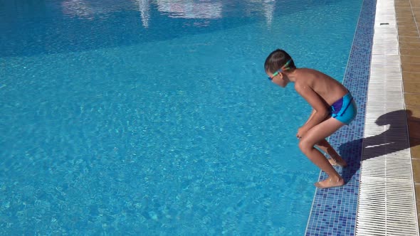 Slow motion jump into a swimming pool. Boy jumping into the water.