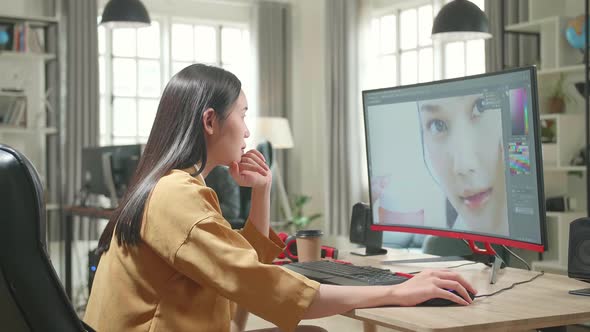 Asian Female Digital Editor Thinking While Works In Photo Editing Software On Computer In Office