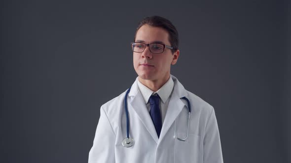 Studio portrait of young professional medical doctor standing over grey background