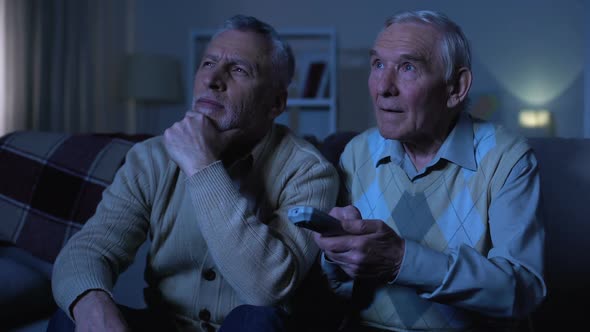 Elderly Men Sitting on Sofa at Home and Switching Channels, Evening Relaxation