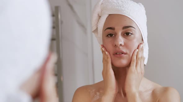 Young Woman Applies a Moisturizer to Her Face and Massage with Her Fingers After a Shower