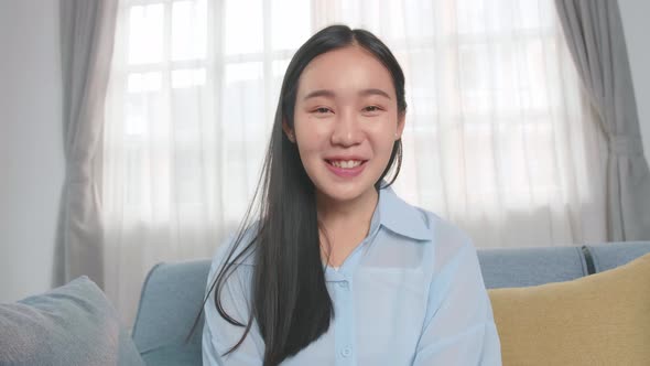 Asian Woman Talking To Camera In Home Living Room