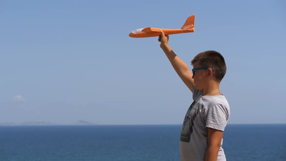 Boy with a Toy Airplane in His Hands on the Background of the Sea