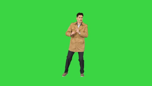 Young Man Wearing Trench Coat Dancing and Having Fun on a Green Screen, Chroma Key.