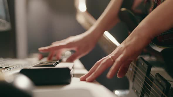 Woman Playing Guitar and Synthesizer Creating Music