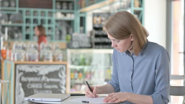 Young Woman Reading Documents in Cafe