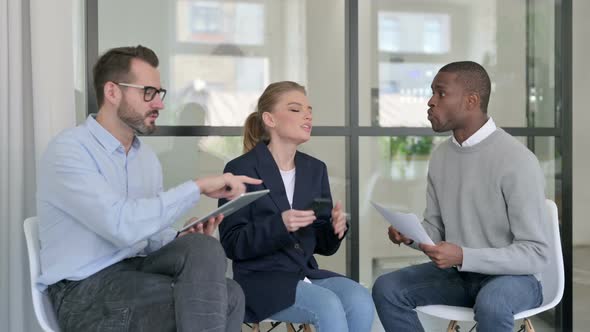 Young Business People Arguing While Holding Tablet Smartphone and Documents