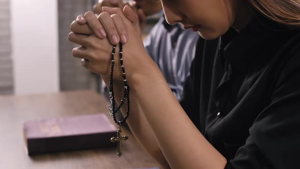 A young Asian Christian couple praying to Jesus Christ in a church.
