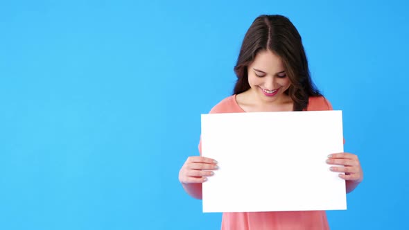 Beautiful woman holding blank placard on blue background