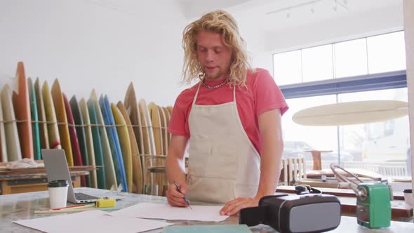 Caucasian male surfboard makers working in his studio