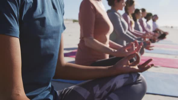 Multi-ethnic group of women doing yoga position on the beach and blue sky background