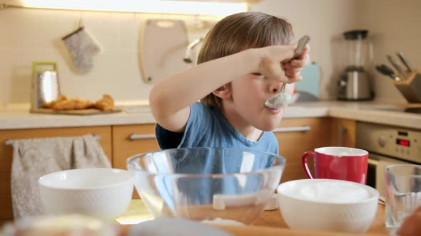 Funny Laughing Little Boy Eating Creme for Baking Pie with Spoon