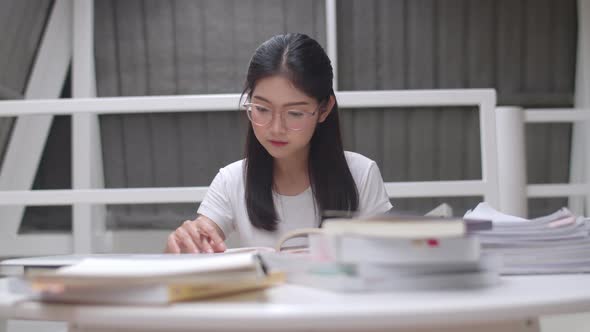 Young undergraduate girl do homework, read textbook, study hard for knowledge and education.