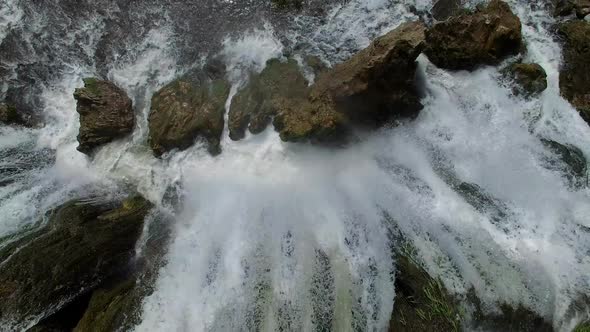 Flying view of waterfall flowing over edge into river