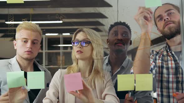 Professional Diverse Team Analyzing Business Strategy Using Glass Board and Sticky Notes